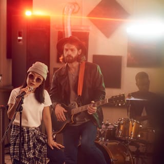 A band in a studio: singer, guitarist and drummer